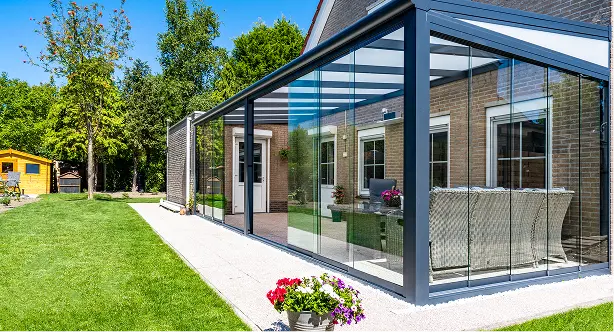Przylegający do domu stalowy ogród zimowy z przesuwanymi szklanymi ścianami i zadaszeniem